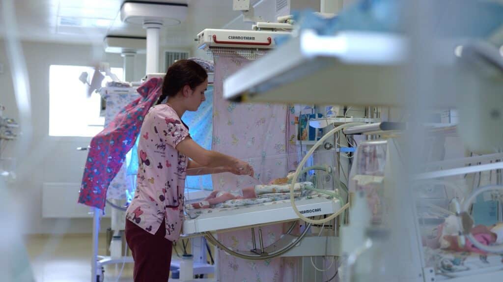 Nurse checks on infant in hospital